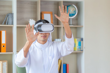 Young arab business man smiling while experiencing new visual sensations through the virtual reality headset in office