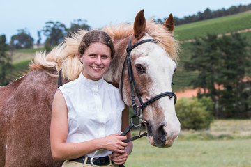 Girl standing next to her Sabino paint horse smiling both facing the camera close up.