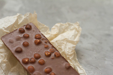 dark chocolate with whole nuts. a whole bar of milk chocolate. chocolate lies on a gray background with foil. the concept of sweets and snacks. sugar. the view from the top. space for text.