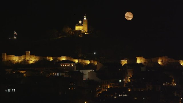 Night view of the famous Tsarevets fortress in the city of Veliko Tarnovo, Bulgaria with the fool moon, 4k