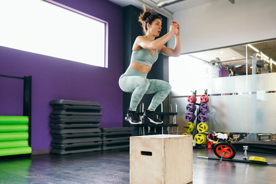 Caucasian female doing box jump workout at gym.