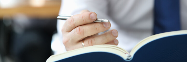 Businessman in white shirt with blueu tie hold diary in hand closeup. Business education concept