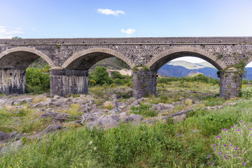 Fototapeta na wymiar Old stone bridge over River Alcantara near Castiglione di Sicilia village, Sicily in Italy