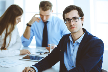 Group of business people discussing questions at meeting in modern office. Headshot of businessman at negotiation. Teamwork, partnership and business concept