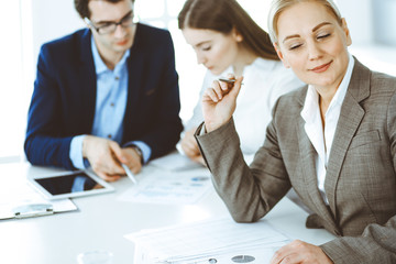 Headshot of business woman at negotiation. Group of business people discussing questions at meeting in modern office. Teamwork, partnership and business concept