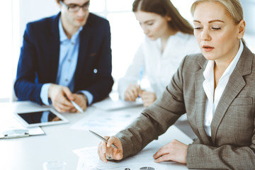 Headshot of business woman at negotiation. Group of business people discussing questions at meeting in modern office. Teamwork, partnership and business concept