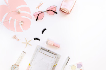 Top view glamour female home office desk workspace with a clipboard, pink sunglasses, beauty accessories and lipstick on white background