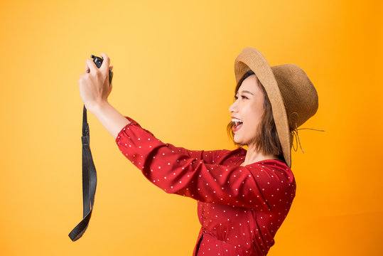 Happy pretty woman take a selfie picture by camera on orange background, asian beauty