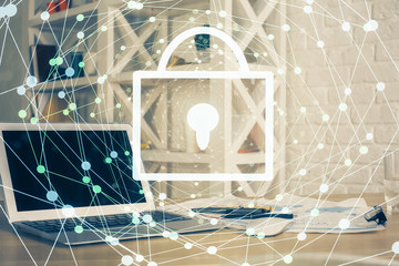 Double exposure of desktop with computer and lock icon hologram. Concept of data safety.