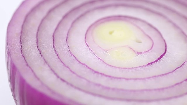 Red onion cut in half rotates spins around its axis, fresh juicy vegetable. Macro top view.