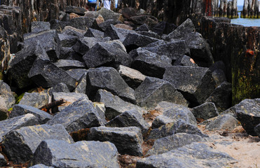 coastline of the sea is strengthened by stones and logs blurred background