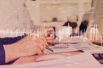 Double exposure of man's hands writing notes of stock market with forex graph.