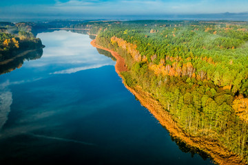 Forest and blue clear lake with chemtrail reflection, aerial view