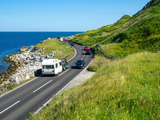 The eastern coast of Northern Ireland and Antrim Coast Road A2, a.k.a Causeway Coastal Route with cars. One of the most scenic coastal roads in Europe