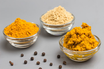 Herbal therapy concept. Spice set: ginger and turmeric powder, turmeric paste on light background..