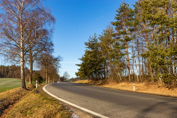 Fototapeta premium Rural asphalt road. Snowless winter in Czech countryside.
