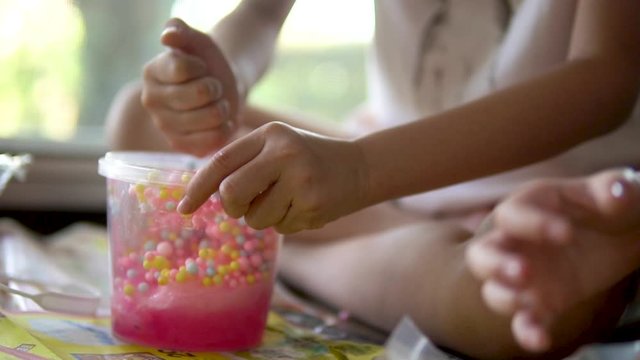 PLAYING WITH HOMEMADE SLIME. Slow motion close up shot of the hands of a young girl playing with homemade slime