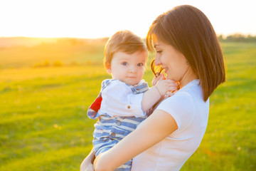Fototapeta premium Mother and lovely son at sunny field with sun glare.