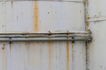old rusted pipes on the exterior of a disused storage tank