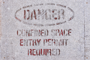 old weathered Danger, Confined Space Entry Permit Required warning sign spray painted on metal background