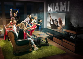 Group of friends watching TV, american football match, championship. Emotional men and women...