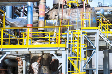 Iron metal industrial plant installations with stairs, fences and pipes, distillation columns at the oil refining chemical metallurgical construction plant