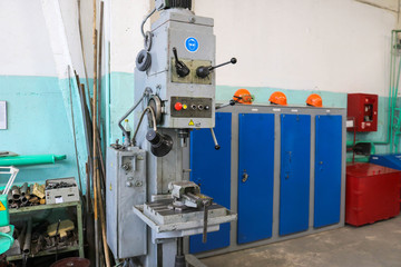 A large powerful iron metal bench-type screw-cutting lathe for the manufacture of parts and spare parts with handles and buttons, vise drills and clamps at an industrial plant