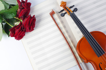 Fototapeta premium Violin with a bow, a bouquet of red roses and clean sheet music.