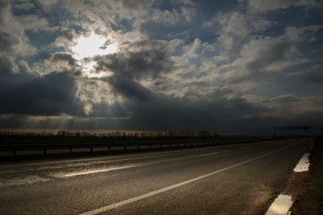 Fototapeta na wymiar Road landscape with dramatic clouds and sun