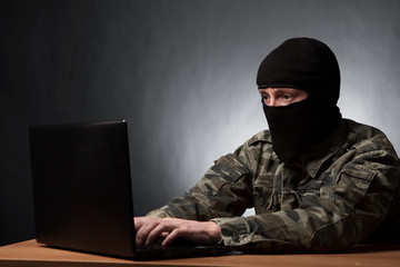 Masked cyber terrorist in military uniform hacking army intelligence