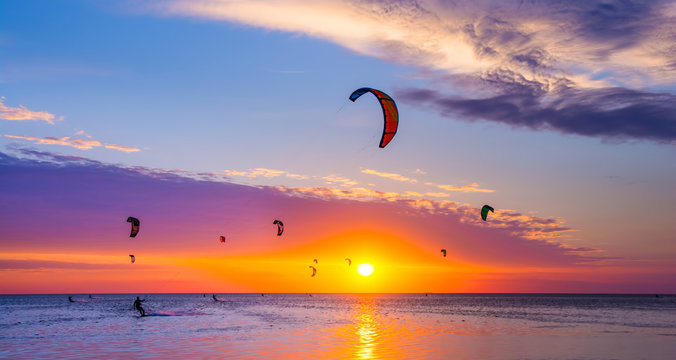 Kite-surfing against a beautiful sunset. Many silhouettes of kites in the sky. Travel concept. Artistic picture. Beauty world. Panorama