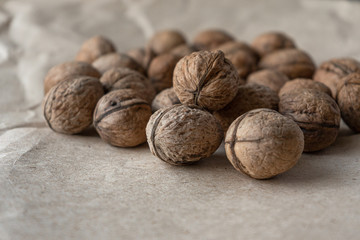 Horizontal handful of walnuts in the shell on an old mint kraft paper, a brown background, a warm beige pattern