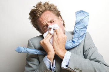 Sick businessman blowing his nose with enough pressure to send his tie flying