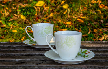 Two cups of tea stand on a wooden surface