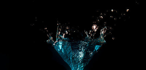 The object falls into the black water until a sponge splits beautifully on a black background.