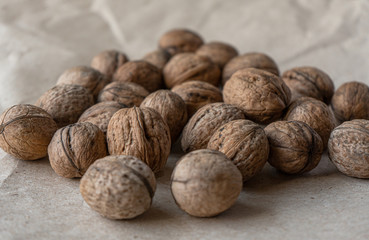 Horizontal handful of walnuts in the shell on an old mint kraft paper, a brown background, a warm beige pattern