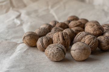 Horizontal handful of walnuts in the shell on an old mint kraft paper, a brown background, a warm beige pattern