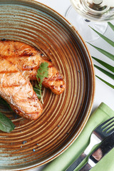 Fish steak on a plate on a white table. Restaurant serving. A look from above.