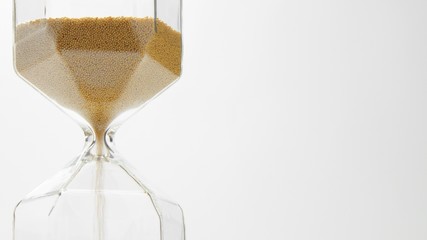 glass sand clock on white with golden balls instead of sand falling. Begining of project conceot....