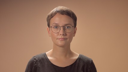 Caucasian woman with a short haircut wears a glasses. Monochrome beige styleof image