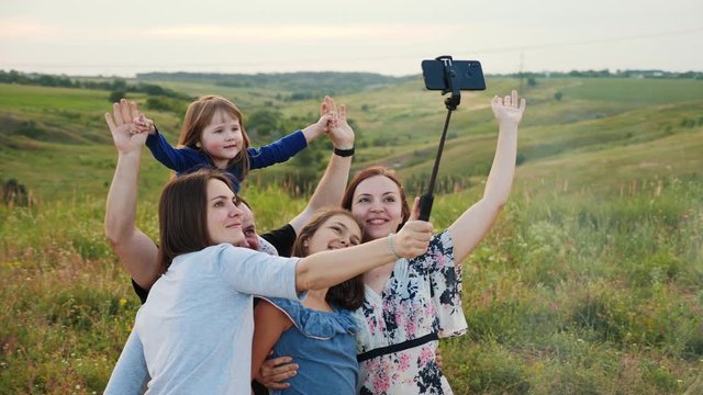 Happy family hugging makes selfie on smartphone while spending time on a picnic.