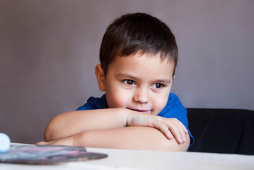 little boy of four years old sits at a table in a blue t-shirt
