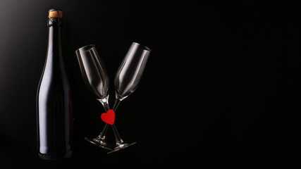 Valentines day greeting card. Sparkling wine with glasses and heart on black background
