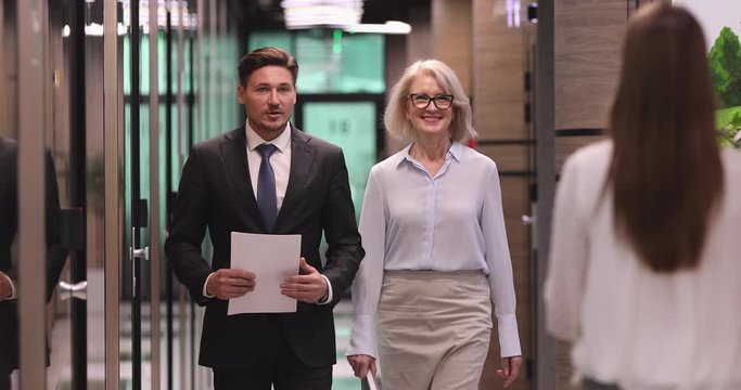 Young intern meeting executives instructing employee in office hallway