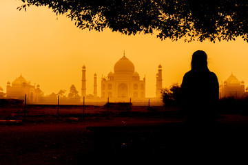 Silhouette female are sitting on the bench and looking  at Taj mahal.