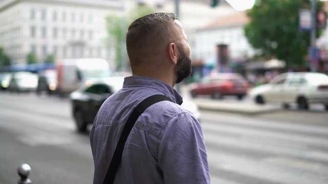 Young man waiting to cross city street
