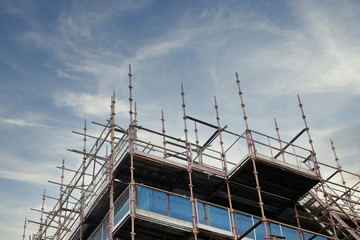 Scaffold platform and poles in blue sky at high level of construction building site