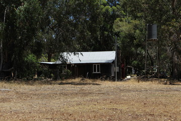 old wooden cottage with overhead watertank