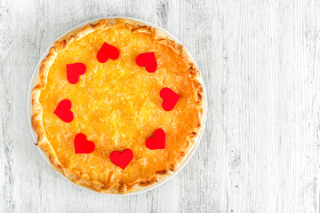 Apple pie decorated with hearts for Valentine day on a whit wooden background.