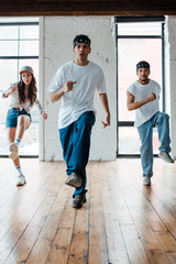 handsome man in headband dancing with multicultural dancers